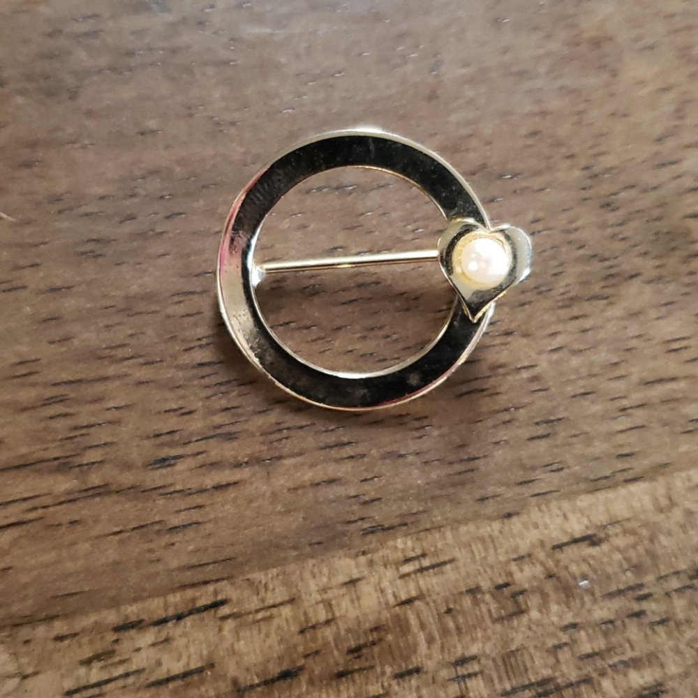 Gold circle brooch with pearl in heart.